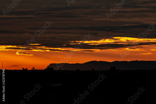 Obraz na płótnie A beautiful and colourful sunset in Bueng Kan City, Thailand showing the skyline of mountains, trees and spotted structures. w salonie