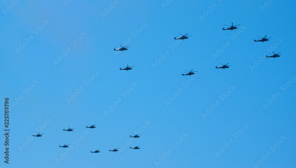 Military helicopters maneuvers in the blue sky. Group combat helicopters in flight during a military demonstration