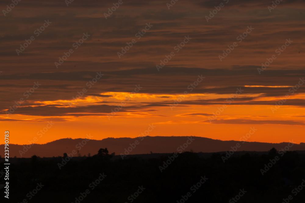 An orange sunset in Bueng Kan. On the horizon is the mountain range Phu Sing.