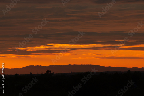 Obraz na płótnie An orange sunset in Bueng Kan. On the horizon is the mountain range Phu Sing. w salonie
