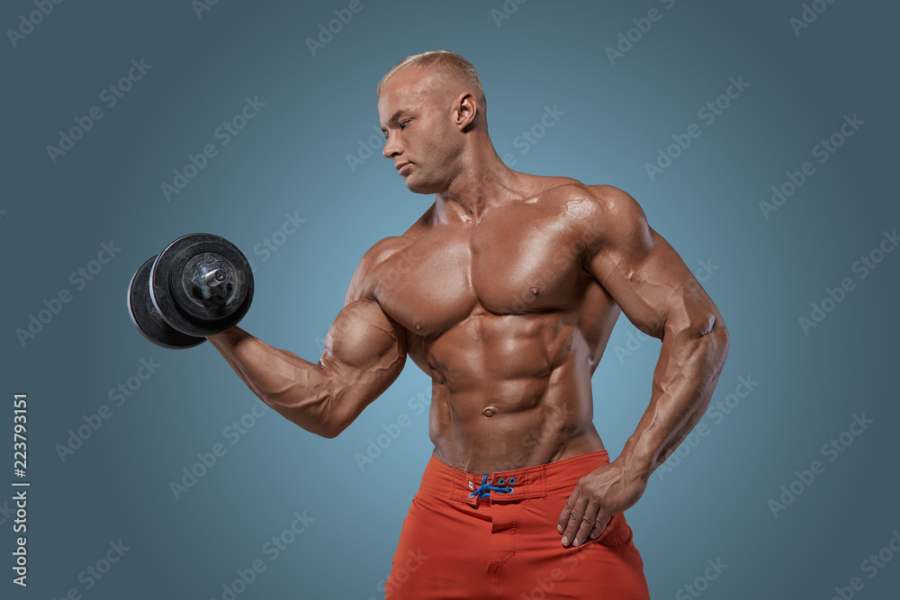 Muscular bodybuilder guy doing exercises with dumbbel