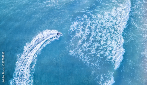 Scooter at the sea surface. Aerial view of luxury floating boat on transparent turquoise water at sunny day. Summer seascape from air. Top view from drone. Seascape with motorboat in bay.  © biletskiyevgeniy.com