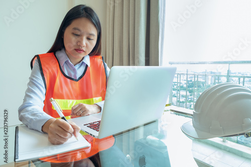 Portrait asia woman engineer writing note on her notebook at contruction site. photo