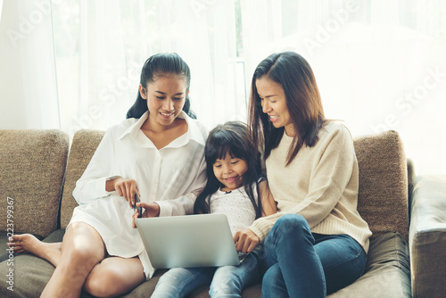happy Young family sitting on sofa and looking at laptop in home