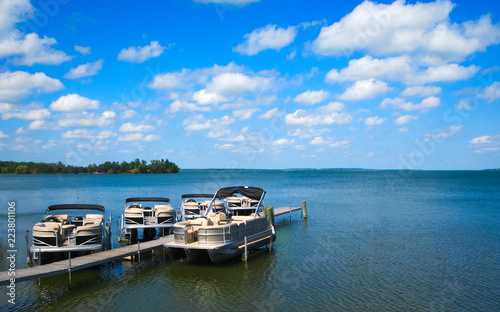 Boat dock with raised pontoons on beautiful lake in northern Minnesota with blue sky and fluffy clouds photo