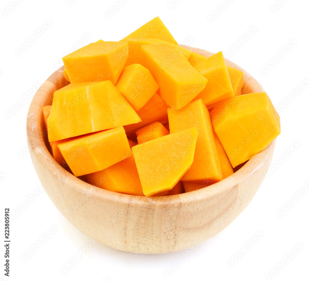 A group of cut and slice butternut squash chunks in wooden bowl on a white background.