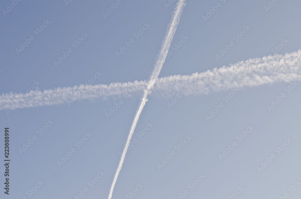The crossing gas clouds in the blue summer sky covering the people with jet streams. The crossing gas clouds in the blue summer sky covering the people with jet streams.