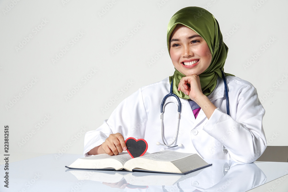 Smiling female doctor holding heart shape studio portrait isolated on white background Smiling female doctor holding heart shape studio portrait isolated on white background