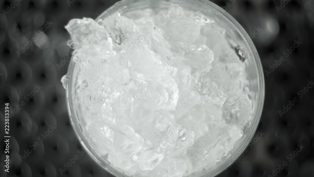 Macro shot of ice crush falling into a cocktail glass with a smoke inside. Making of cocktail. Macro shot of ice crush falling into a cocktail glass with a smoke inside. Making of cocktail.