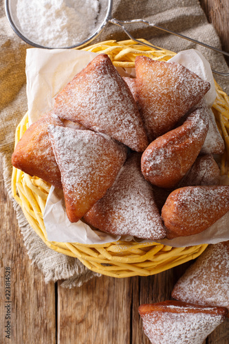 Soft Mandzi – East African Doughnuts made with grated coconut,  spiced with cardamon, nutmeg and fried close-up in a basket on a table. Vertical top view