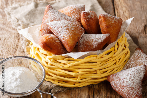 Delicious deep-fried donuts East African Mandazi with powdered sugar close-up in a basket. horizontal