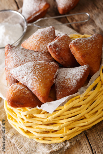 East African Mandazi  (dabo) donuts with powdered sugar close up in the basket. vertical