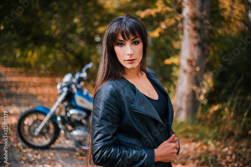 The girl in a black leather jacket with long hair. Motorcycle in the background