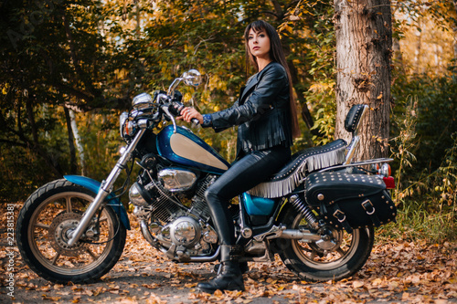 Girl on a motorcycle in a black jacket and leather pants. Women biker