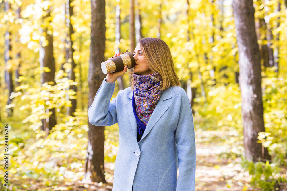 Fall, nature, people concept - young brunette woman drink coffee in autumn park Fall, nature, people concept - young brunette woman drink coffee in autumn park