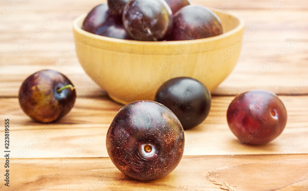 Wooden bowl with plums on the table. Wooden bowl with plums on the table.