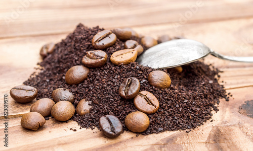 Heap of ground coffee and coffee beans with spoon on the table.