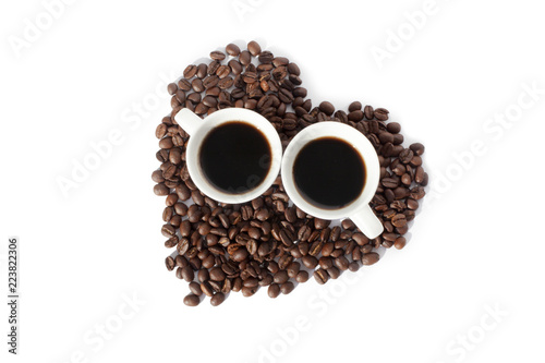 Two cups of black coffee and a heart made of coffee beans on white backgroung isolated top view