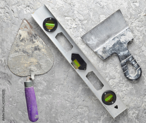 Building tools on a gray concrete background. Spatula, trowel, level, level, top view.