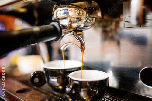 Close-up of espresso pouring from coffee machine into cups. Professional coffee brewing, barista details