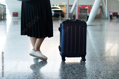 Traveler woman legs walking carrying a suitcase in an airport