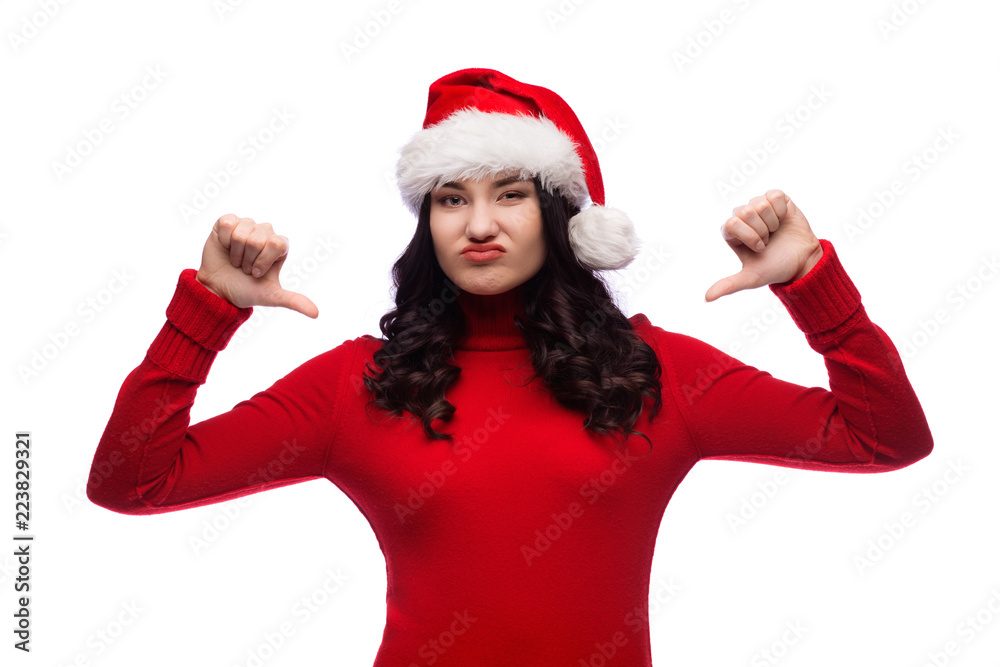 Brunette girl wearing christmas hat showing dislike with thumbs down, rejection concept, Isolated Brunette girl wearing christmas hat showing dislike with thumbs down, rejection concept, Isolated