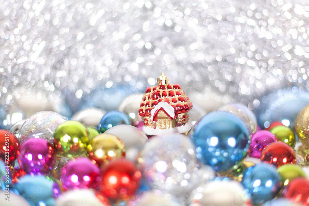 Fototapeta premium Christmas and New Year's toy fairy tale red house in snowdrifts and snow of Christmas balls and tinsel in different bright colors, holiday decorations, ornaments, lights, bokeh close up macro