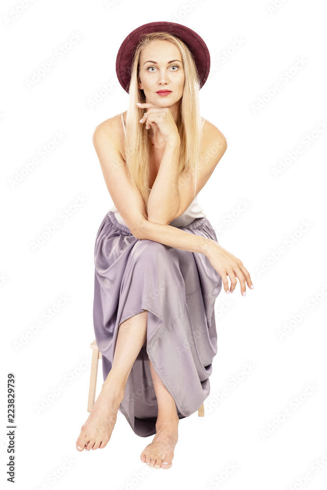 Naklejka premium Young beautiful woman in hat sits smiling, isolated on white background