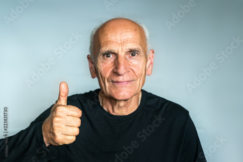 Happy positive elderly man in a black shirt, thumb up, everything's cool.