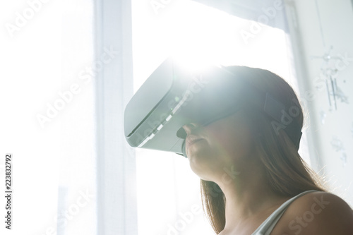 Young female playing game in VR glasses. Beautiful woman  using modern virtual reality glasses photo