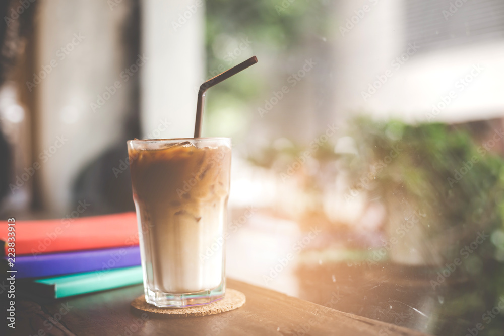 Close up of a cup of cappuccino or latte coffee with a white foam on a wooden background in a cafe, Book on the table. Close up of a cup of cappuccino or latte coffee with a white foam on a wooden background in a cafe, Book on the table.