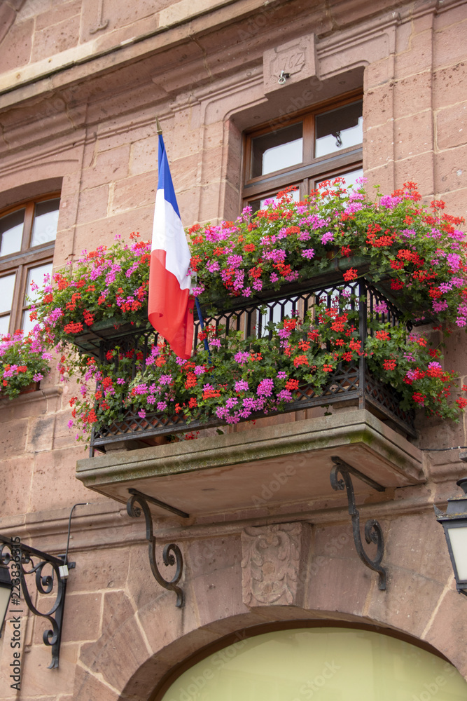 Naklejka premium Drapeau français sur un balcon fleuri