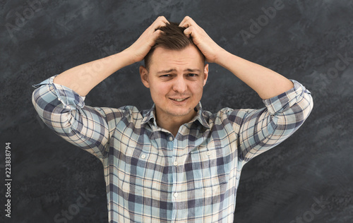 Young desperate man touching his head