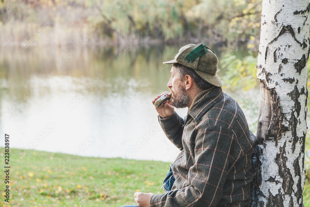 man with beard in plaid jacket drinks from round flask man with beard in plaid jacket drinks from round flask
