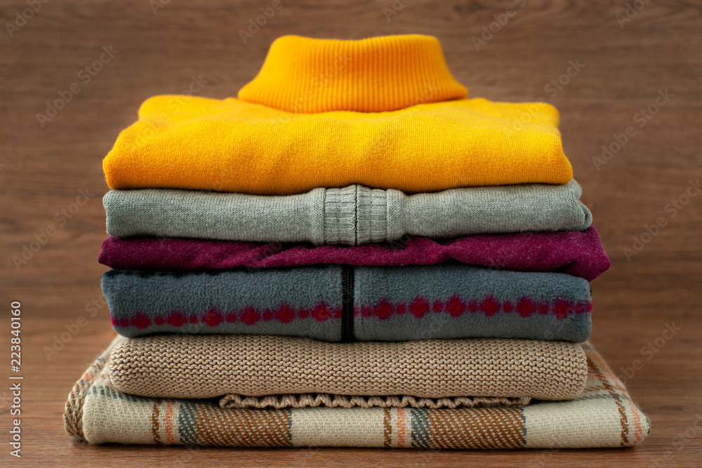 A pile of warm clothes for the cold seasons. Turtlenecks, sweaters, a vest for autumn and winter. Clothes made of soft knitwear and fleece. Fashion, style and design.