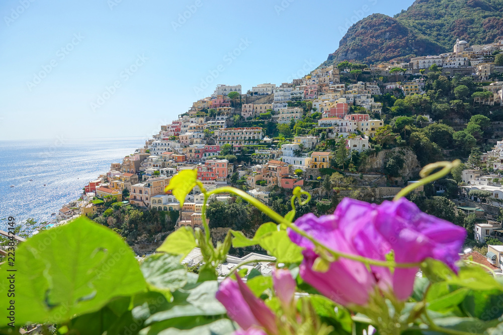 CLOSE UP: Cool shot of coastal town in Italy behind the purple flower blossoms.
