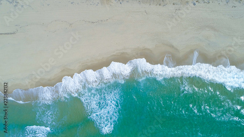 COPY SPACE: Flying above turquoise ocean waves washing the empty sandy beach. © helivideo