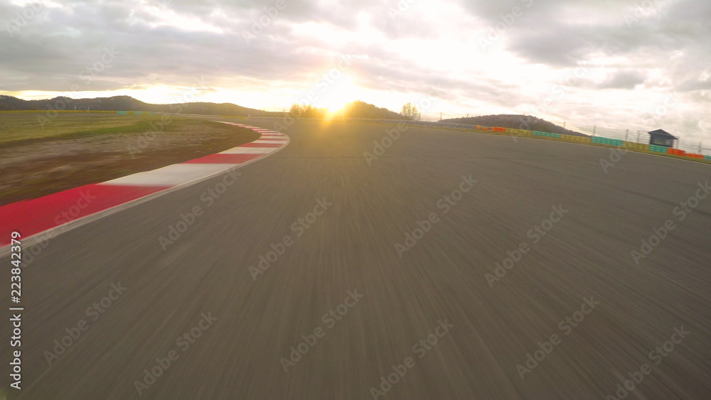 POV: Driving a fast car along the scenic asphalt racetrack on a cloudy evening.