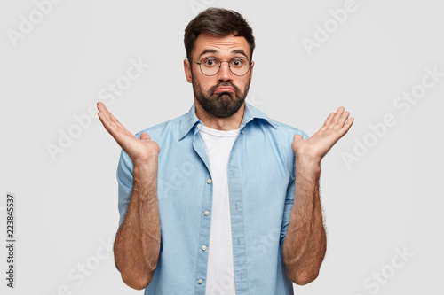 Unaware clueless bearded handsome man shrugs shoulders with uncertainty, cannot answer question, being uninterested in something, stands against white background. I dont care about it anymore