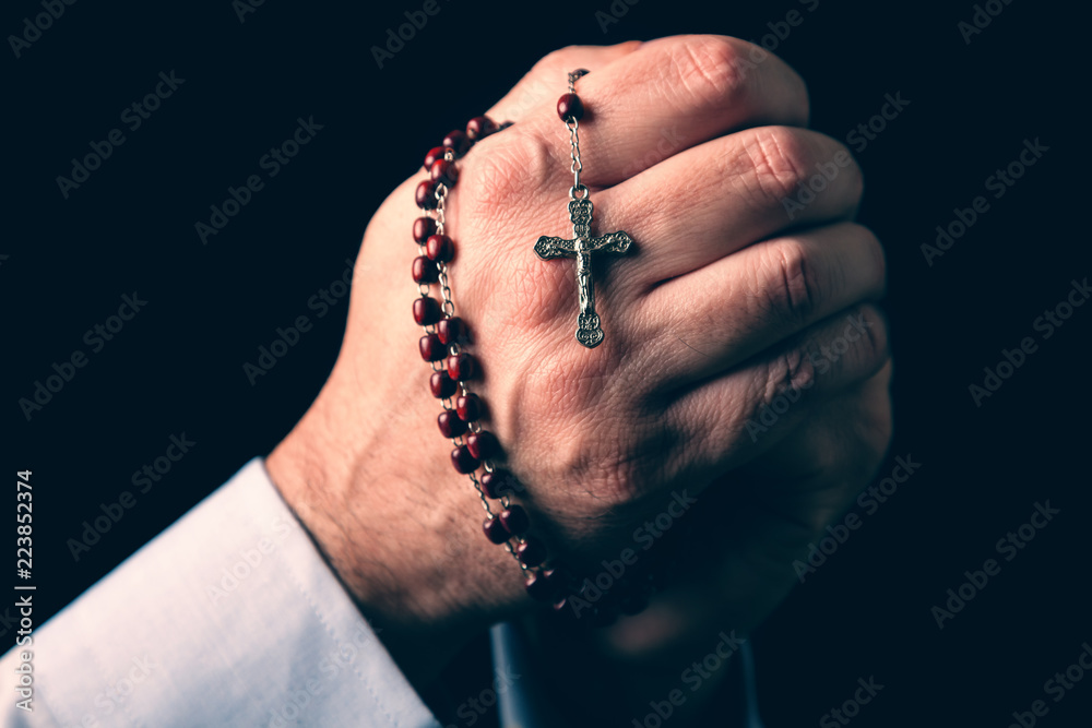 Male hands praying holding a rosary with Jesus Christ in the cross or  Crucifix on black background. Mature man with Christian Catholic religious  faith Stock Photo | Adobe Stock