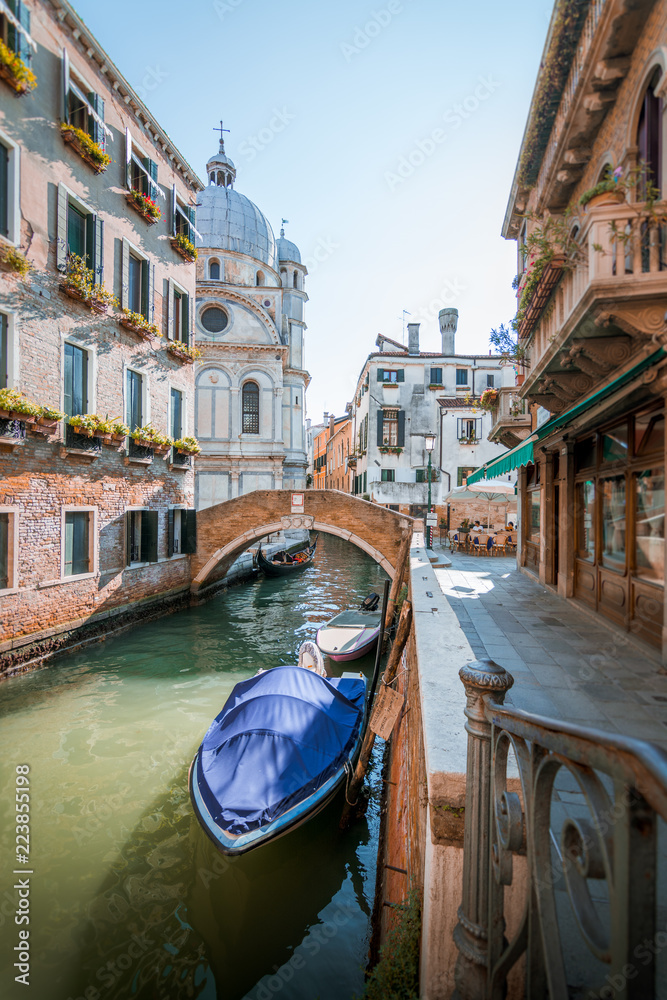 Historical architecture and landmarks in Venice old town in Italy. Narrow streets with colorful buildings surrounded by tourists. Beautiful scenery of romantic canals and boats.