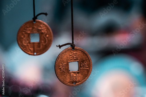 Oriental, magical pendants. Traditional asiatic and chinese currency, transformed into fortune coins with powerful engravings. Bronze, copper, gold necklace, black thread, blurry background.  photo