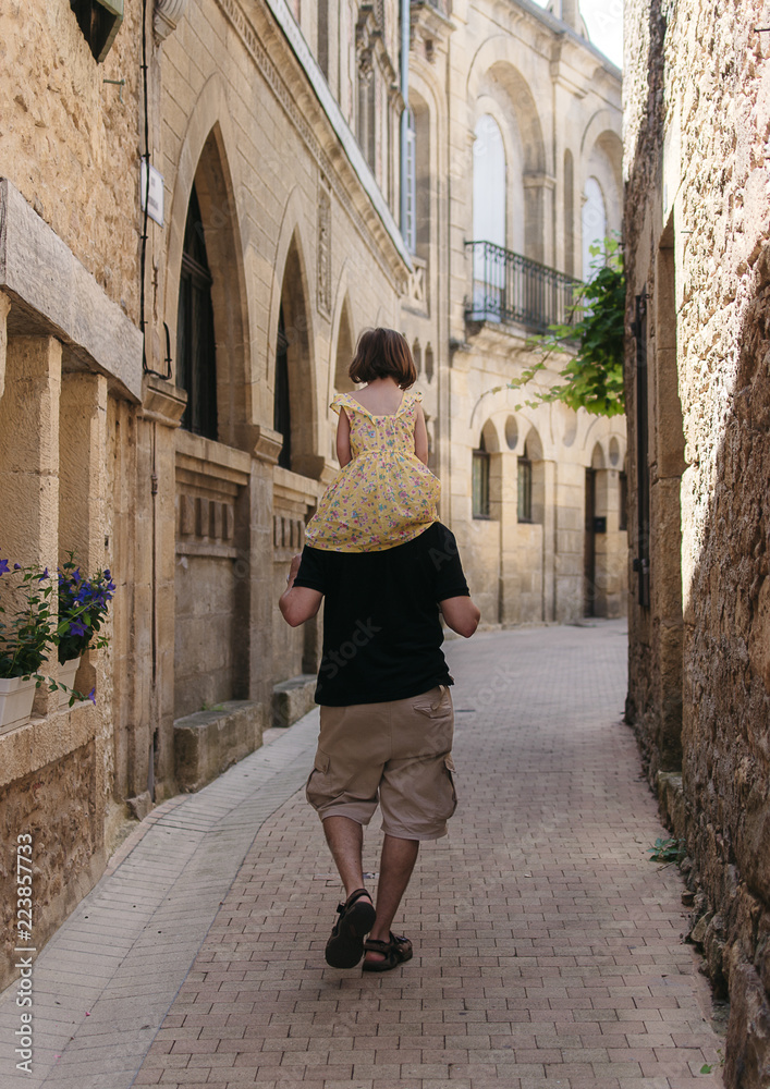 Padre e hija caminando por una calle en un pueblito de Francia