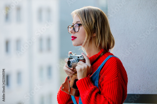 Young girl with vintage camera and glasses at balcony