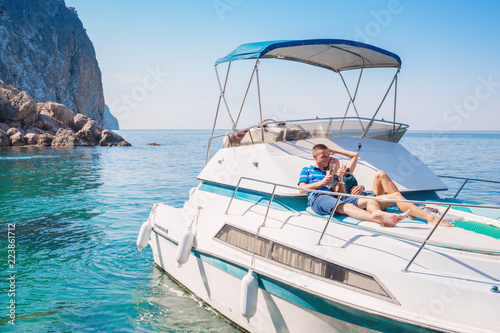 Couple relaxing on a yacht at sea on the background of a beautiful mountain landscape. Happy wealthy man and a woman by private boat have sea trip.