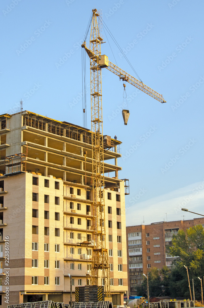 Construction of a multi-storey building. Crane at work. Workers on the top floor. Brick. Russia Construction of a multi-storey building. Crane at work. Workers on the top floor. Brick. Russia