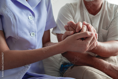 Comforting hand. Young nurse holding old man's hand. © Baan Taksin Studio