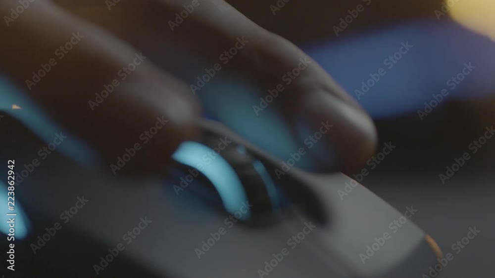 Video gamer or hacker. Hand on computer mouse with RGB backlight. Close-up dolly panning. Shallow depth of field