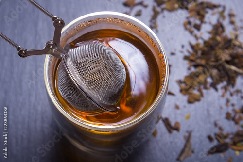 Double walled glass with tea and stainless steel tea infuser photo