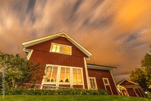 long exposure night photo of traditional red wooden swedish house and dark heavy clouds © Alexandre Patchine